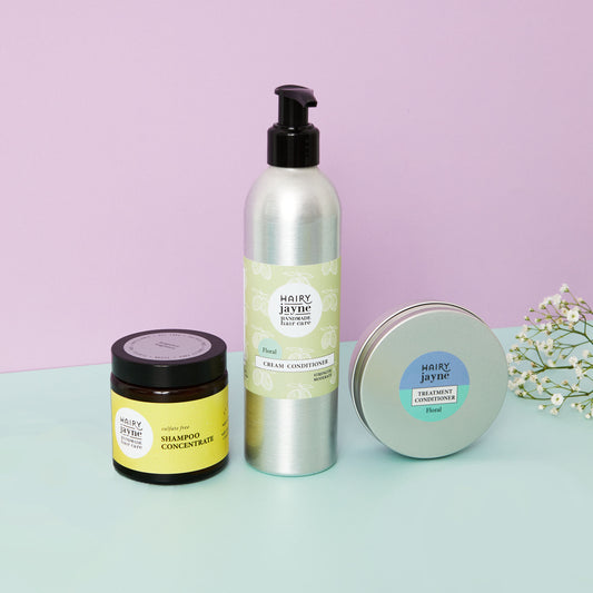 Set of Hairy Jayne hair care products on a light green surface with a pink background