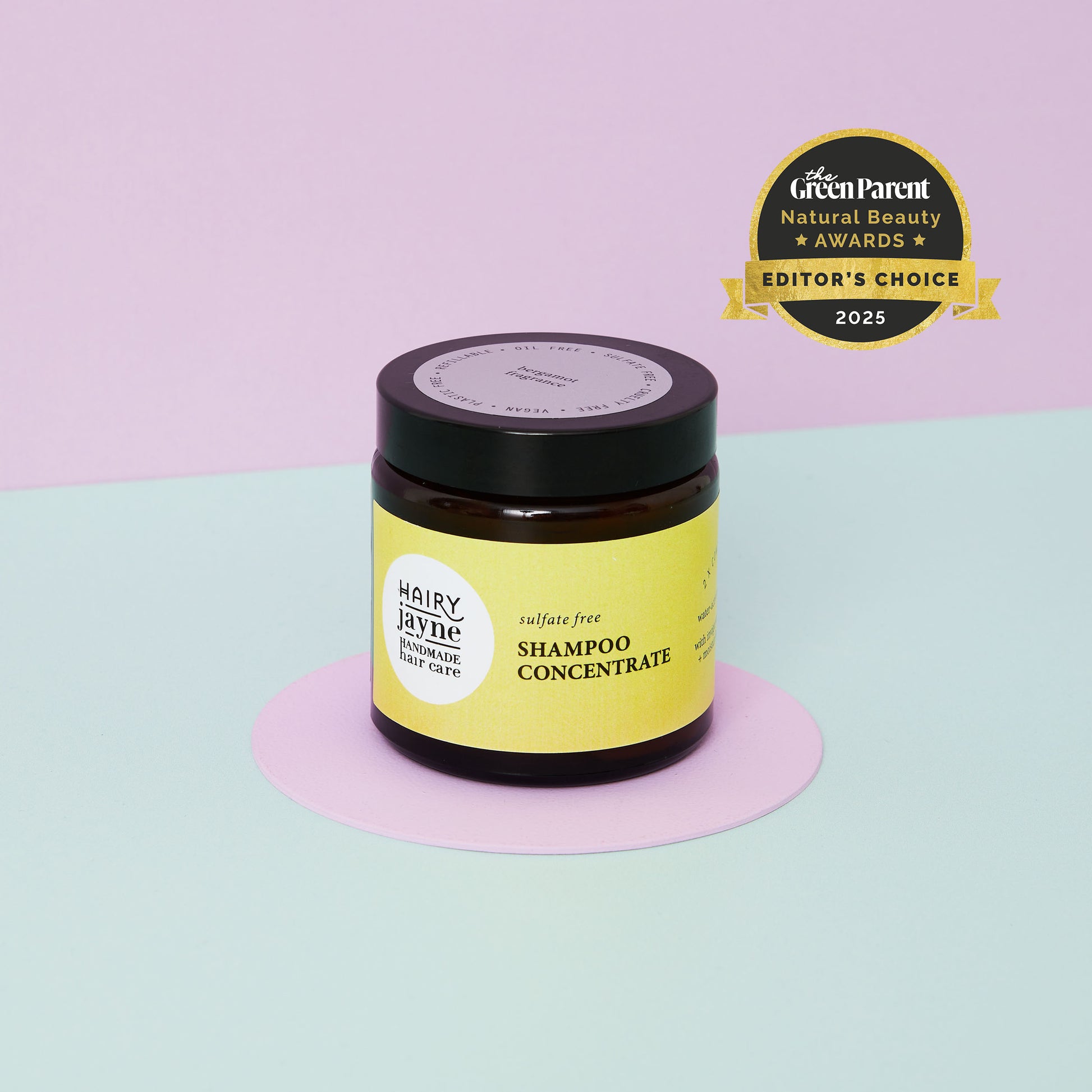 Shampoo concentrate jar with a 'Green Parent' award on a pastel background