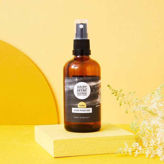 Hairy Jayne hair perfume bottle on a yellow background with flowers.